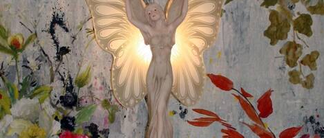A decorative angel statue with wings, placed on a table against a floral background.