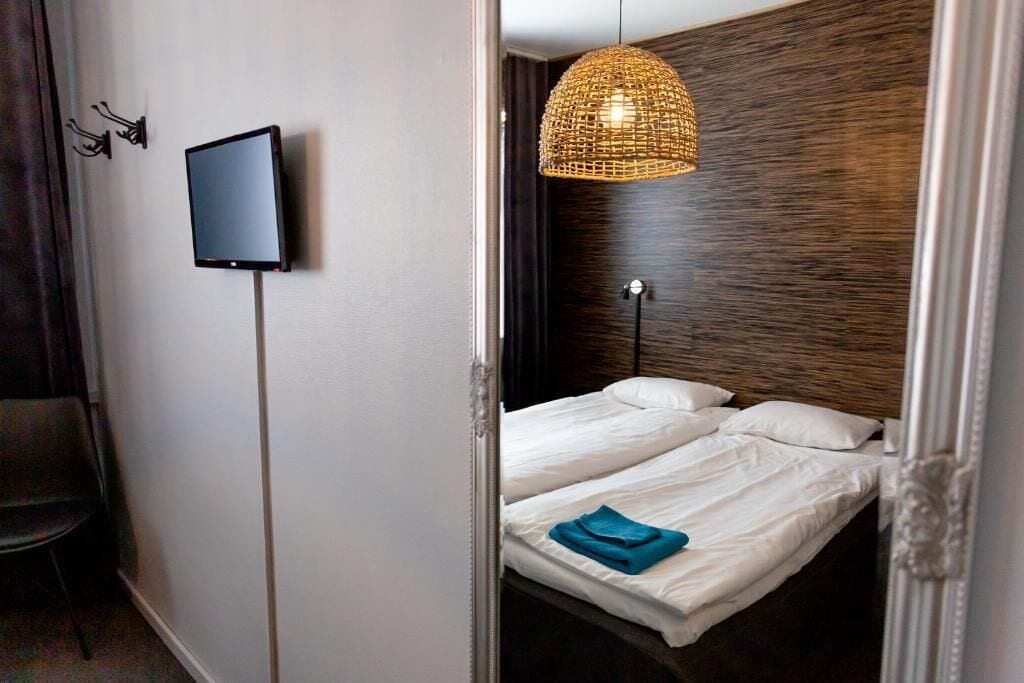Ein Hotelzimmer mit einem Bett, einem Fernseher und einer einzigartigen gewebten Leuchte.