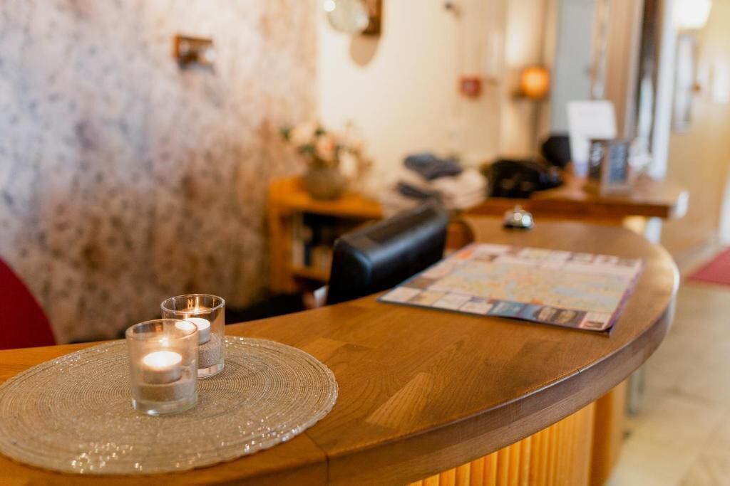 A wooden reception desk with a placemat, two candles, and a menu.