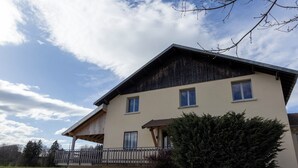 Une maison à deux étages avec un balcon, un garage et une pelouse bien entretenue.