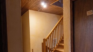 Un escalier en bois mène à un niveau supérieur, et une porte en bois se trouve au bout.