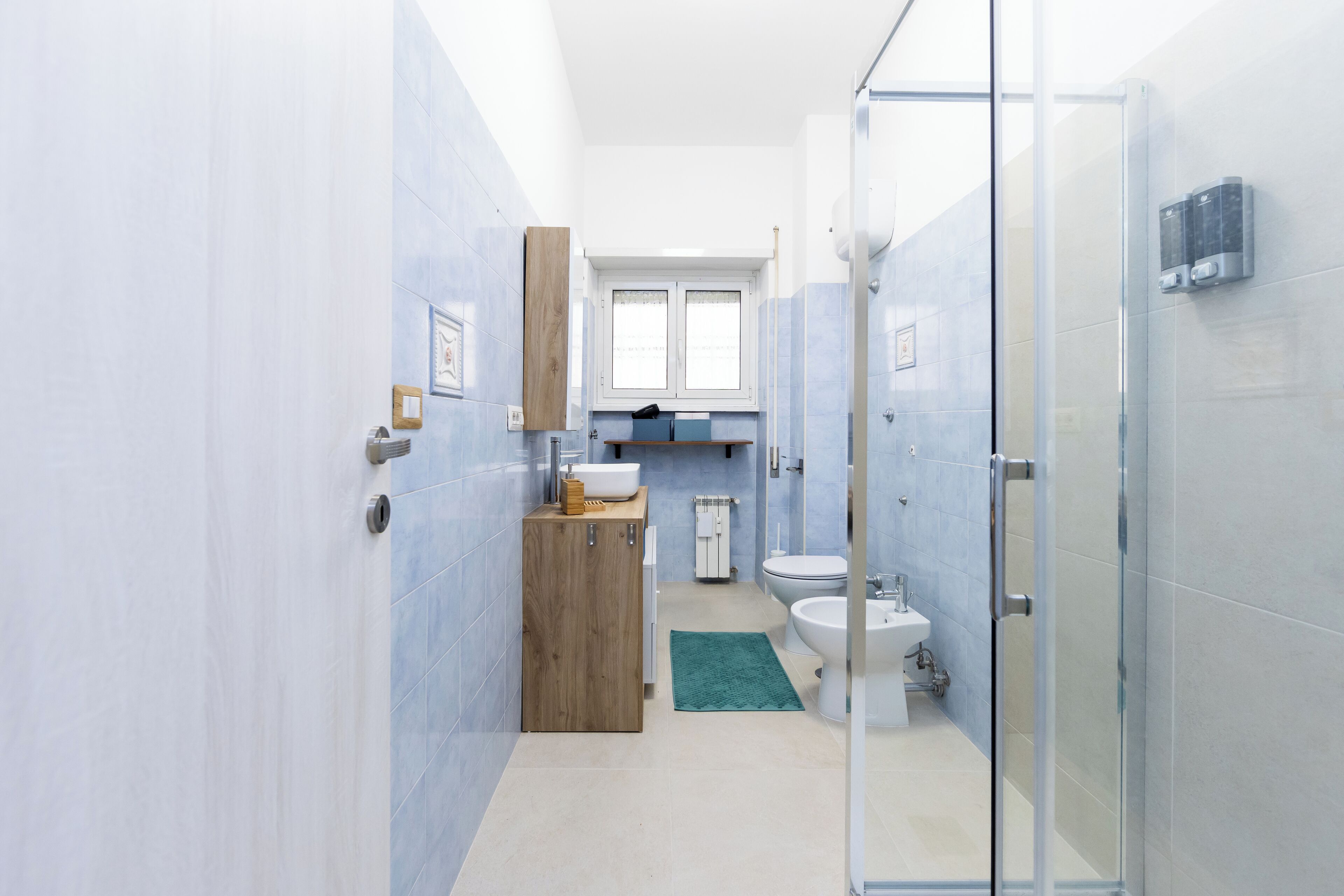A modern bathroom with a glass shower enclosure, a wooden vanity, a white sink, and a toilet.
