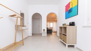A hallway with a wooden rack, a white cabinet, and a colorful painting on the wall.