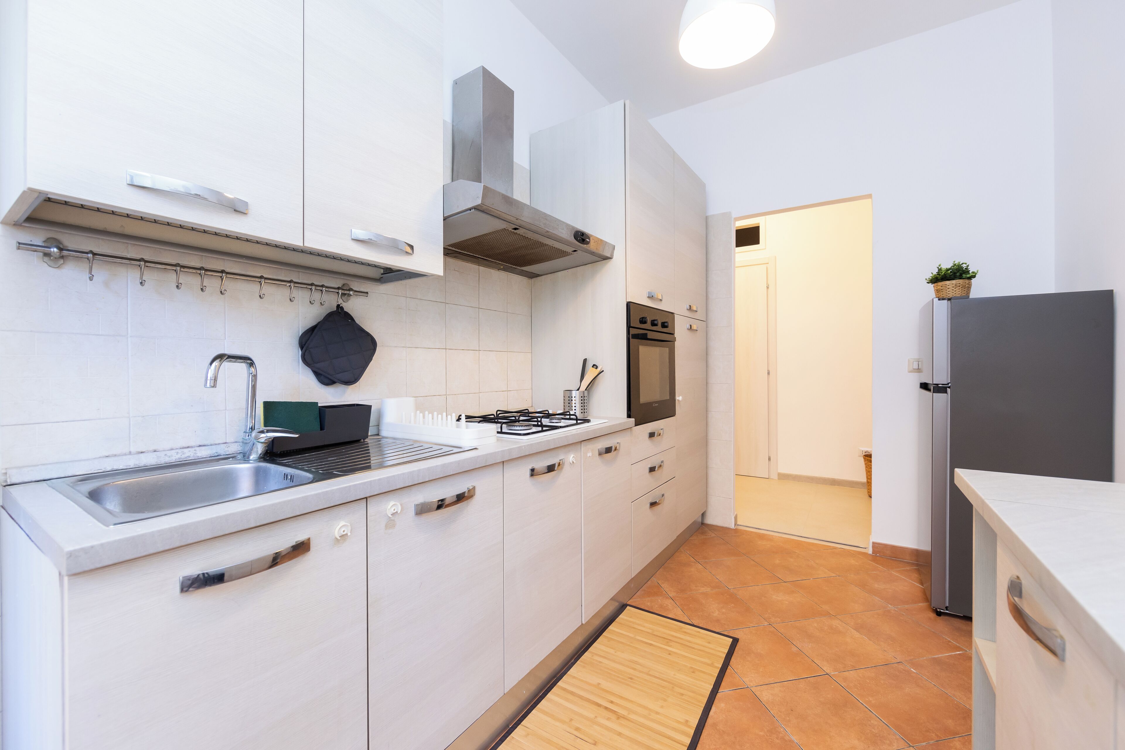A modern kitchen with white cabinets, a stainless steel sink, a gas stove, and a built-in oven.