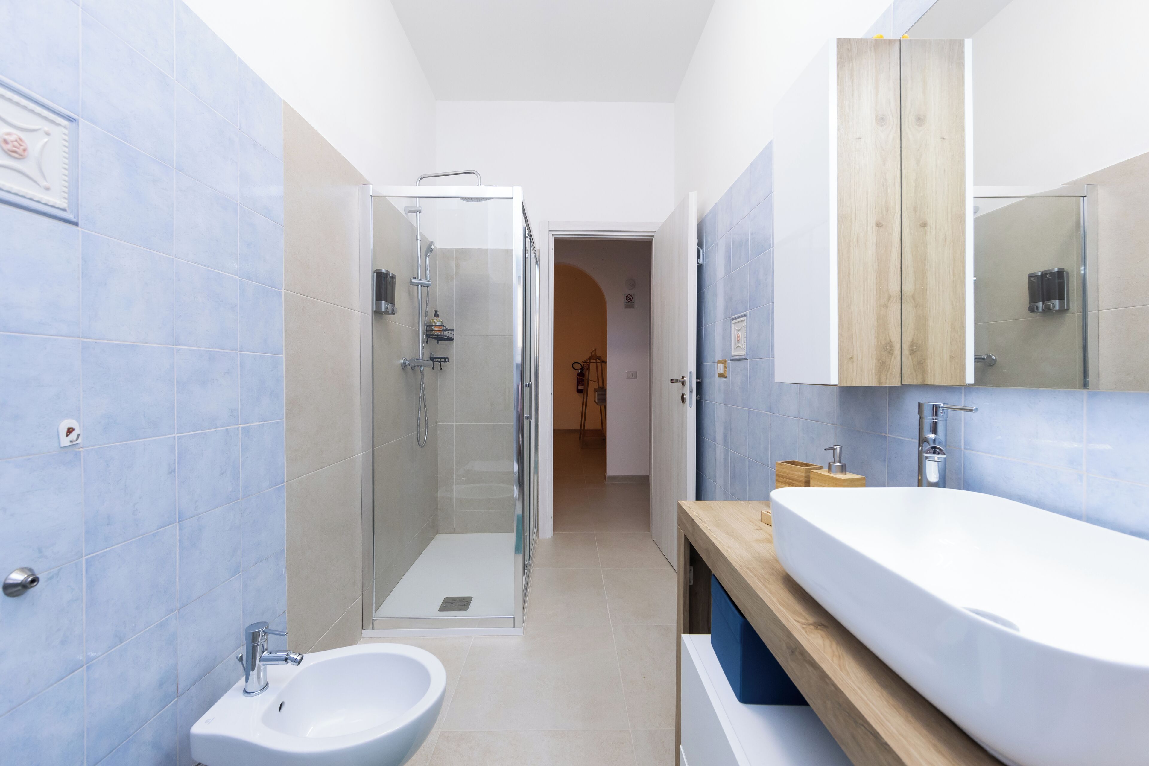 Une salle de bain moderne avec une douche à parois de verre, un lavabo blanc et un meuble-lavabo en bois.