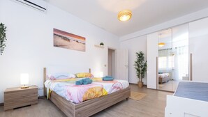 A modern bedroom with a wooden bed, bedside tables, a large window, and a view of the beach.