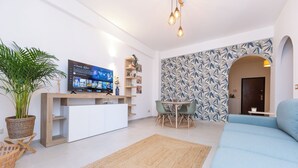 A modern living room with a TV, a dining area, and a blue sofa.
