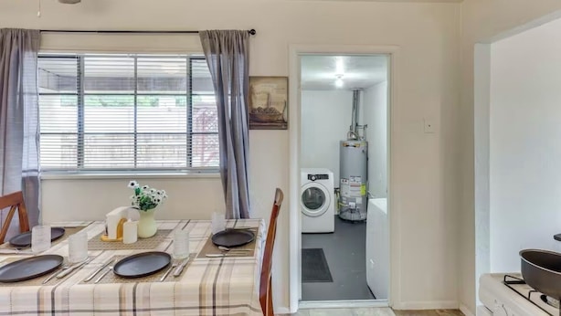 A dining area with a table set for four, a ceiling fan, and a window with curtains.