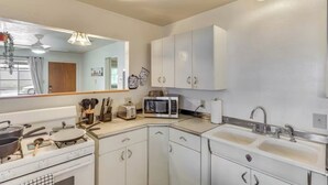 A kitchen with white cabinets, a microwave, a stove, and a sink.
