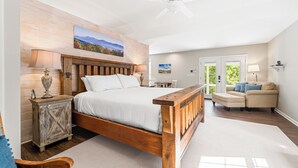 Un dormitorio con una cama de madera, una mesita de noche, un aparador, una silla y un sofá.