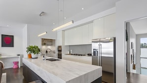 Une cuisine moderne dotée d’un grand îlot central, d’appareils électroménagers en acier inoxydable et d’un design minimaliste.