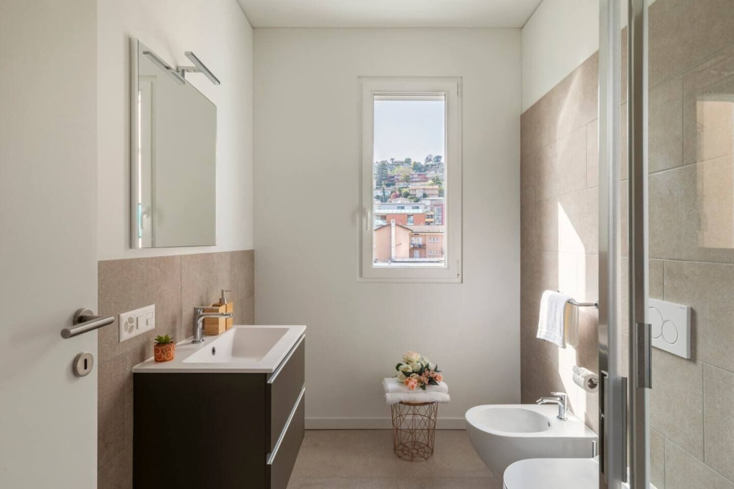 Ein modernes Badezimmer mit großem Fenster, Waschbecken, Toilette und Badewanne.