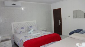 Une chambre à coucher avec un lit, une table de chevet, une commode, une porte et un miroir au mur.