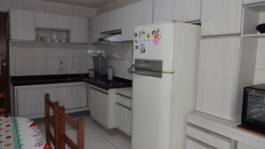 Une cuisine avec des armoires blanches, un réfrigérateur, une cuisinière et un four à micro-ondes.