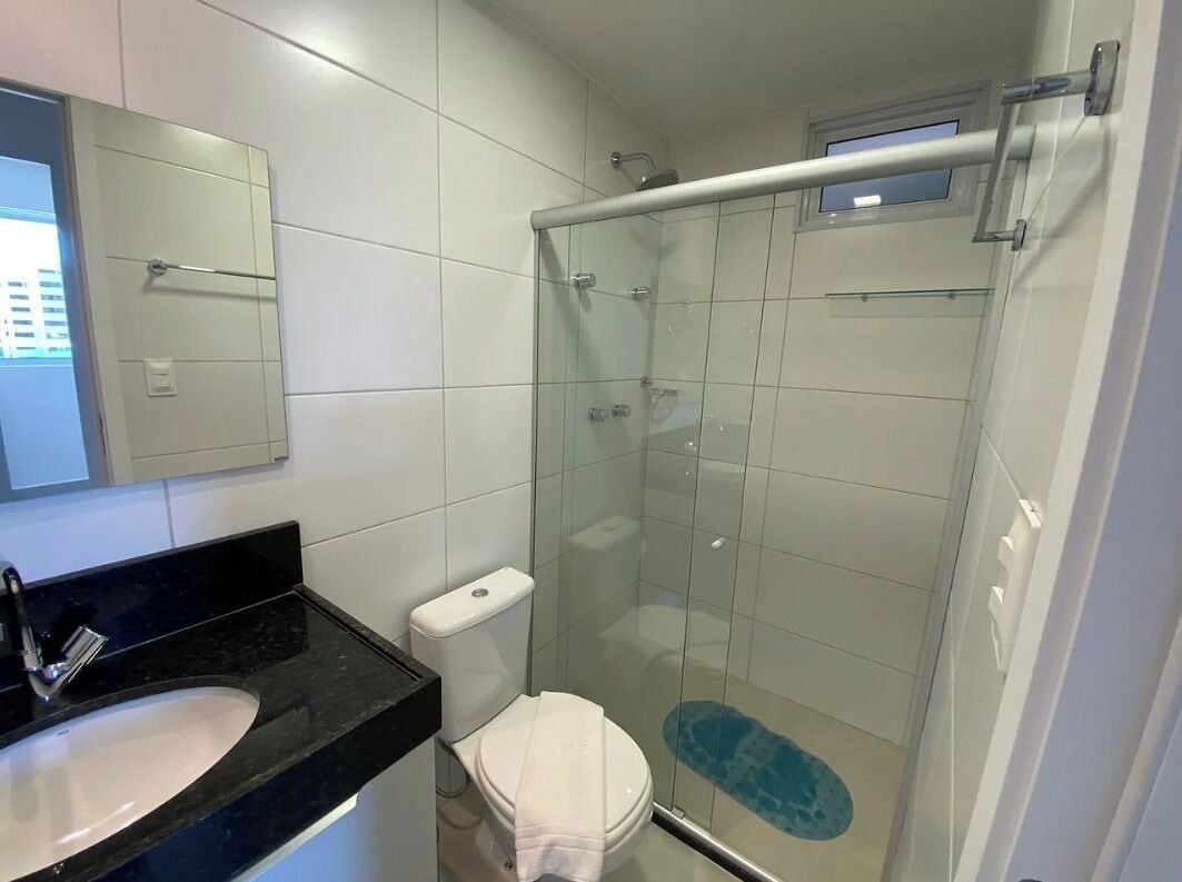 A bathroom with a glass-enclosed shower, a white toilet, and a black countertop sink.