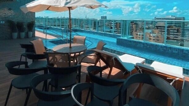 A rooftop pool area with outdoor seating and a view of the city skyline. - Edificio Promenade II - Apt 604 (Maceio)
