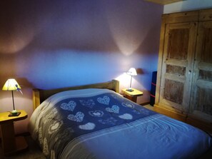 Une chambre à coucher comprenant un lit, deux tables de chevet, une armoire en bois et deux lampes.