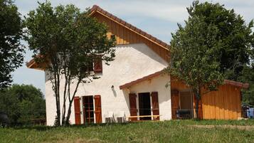 Et rustikt hus med hvide facader, træpersienner og et skråt tag.