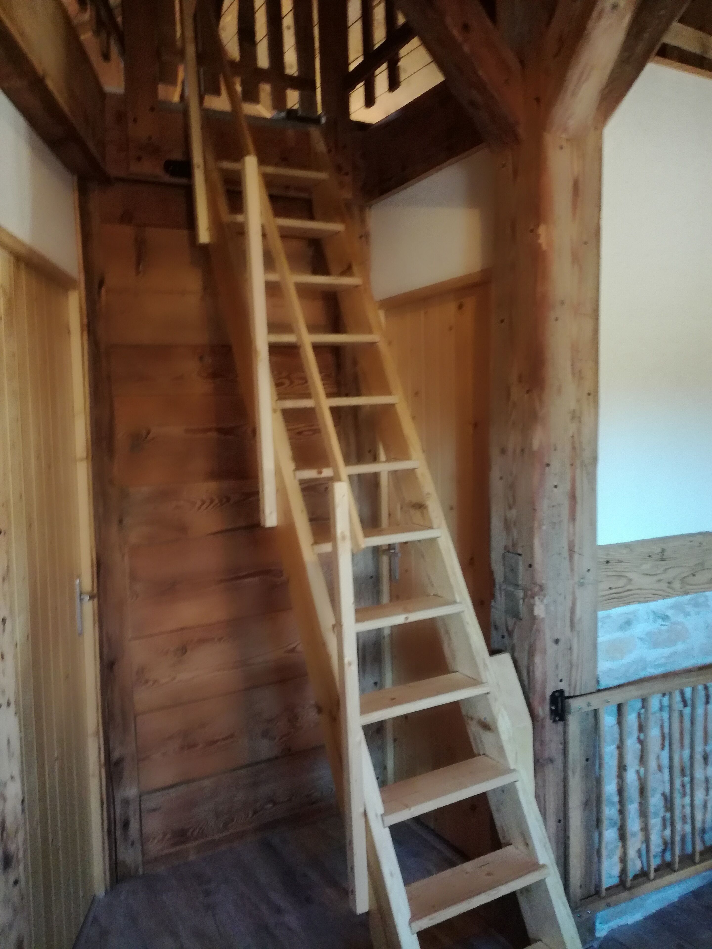 A wooden staircase with a metal railing, leading to a higher floor.
