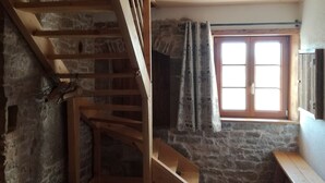 A rustic room with a wooden staircase, stone walls, a window with curtains, and a bench. - Gîte 'La Valentine', secluded country house in the heart of nature (Le Barboux)