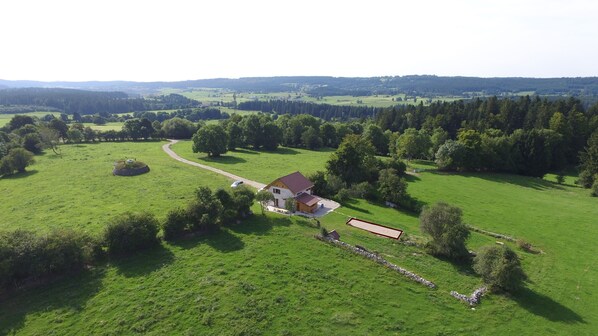 Une propriété rurale comprenant une ferme, des champs verdoyants et un mur de pierres.