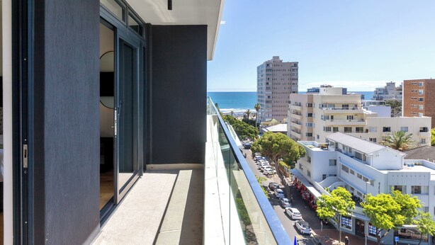 A balcony with a view of the ocean and city buildings. - The Sage | Modern and Bright Sea Point Apartment (Cape Town)