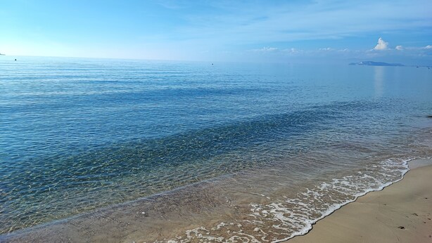 A beach with clear water and a distant island. - Charming 2-bedroom cottage with WiFi, AC in lovely Quartu Sant'Elena (Quartu Sant'Elena)