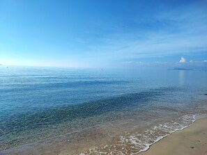 A beach with clear water and a distant island.