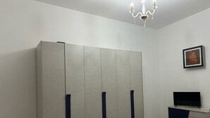 A bedroom with a bed, a wardrobe, a television, and a chandelier. - Maison Dominique (Reggio Calabria)