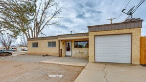 Einbungalow mit Garage, einer kleinen Veranda mit zwei Stühlen und einem großen Baum im Hintergrund.