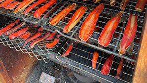 Una barbacoa amb diverses reixes plenes d'aliments en espetxes.