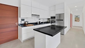 Une cuisine moderne avec des meubles blancs, un plan de travail noir et des appareils électroménagers en acier inoxydable.