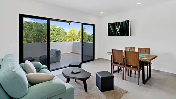 Un salon moderne comprenant un canapé, une table basse et un coin repas avec des chaises et une table.