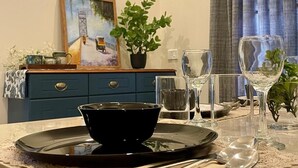 Una mesa de comedor con un tazón negro, copas de vino y una planta en maceta.