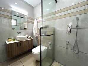 Une salle de bain moderne avec une douche à l’italienne en verre, un lavabo blanc et un meuble-lavabo en bois.