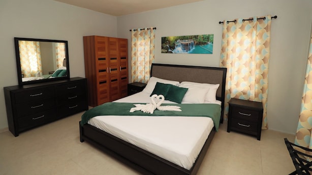 Een slaapkamer met een bed, een dressoir, een nachtkastje, een kledingkast en een plafondventilator.
