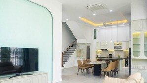 Un salon moderne doté d’un téléviseur à écran plat, d’un canapé et d’un coin repas avec des chaises et une table.