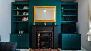 Un salon aux murs de couleur turquoise, doté d’une cheminée et de bibliothèques intégrées.