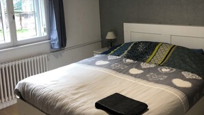 A bedroom with a bed, a window, a radiator, and a nightstand with a lamp. - Gîte 'A deux pas du ciné', located in the center of Maîche (Maîche)