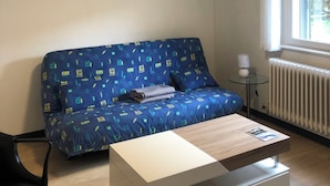A small, modern living room with a blue sofa, a white coffee table, and a framed picture on the wall. - Gîte 'A deux pas du ciné', located in the center of Maîche (Maîche)