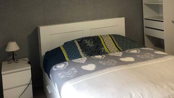 A bedroom with a bed, bedside table, lamp, and wardrobe.