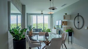 Een moderne eetruimte met een glazen tafel, witte stoelen en potplanten.