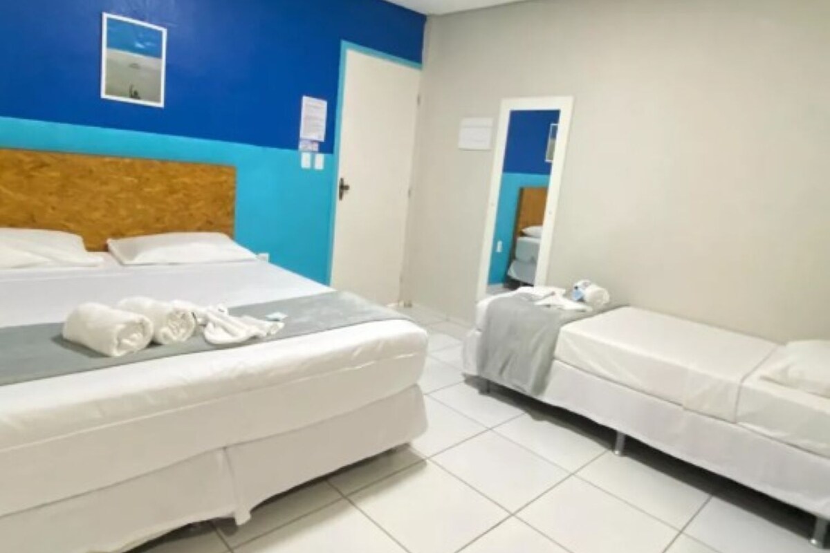 A hotel room with two beds, a wooden headboard, a mirror, and a blue accent wall.