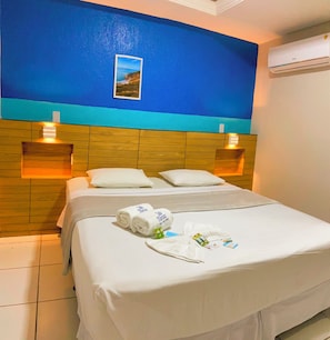 A hotel room with a wooden headboard, two pillows, a neatly made bed with white linens, and a photo of a coastal landscape on the wall. - Pousada Vila Mansa Jeri (Jijoca de Jericoacoara)