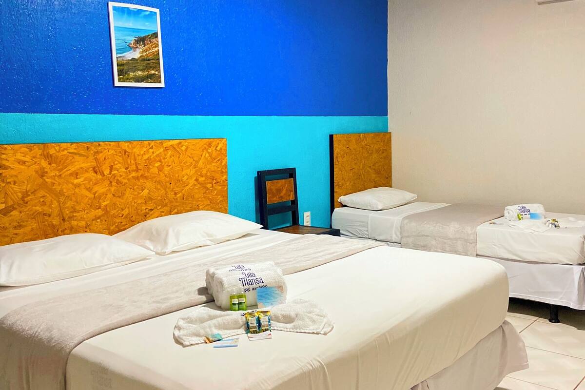 Une chambre d’hôtel avec deux lits, une décoration aux couleurs bleu et blanc, un tableau encadré au mur et un appareil de climatisation blanc.