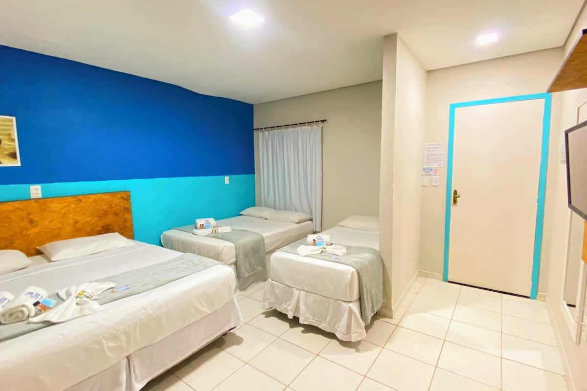 Une chambre d’hôtel avec deux lits, une télévision et une porte ornée d’une bande bleue.