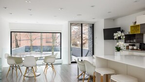 Eine moderne Küche mit großem Fenster, weißen Stühlen und einer Bar.