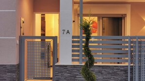 A modern building entrance with a metal gate, a small tree, and a number '7A' sign.