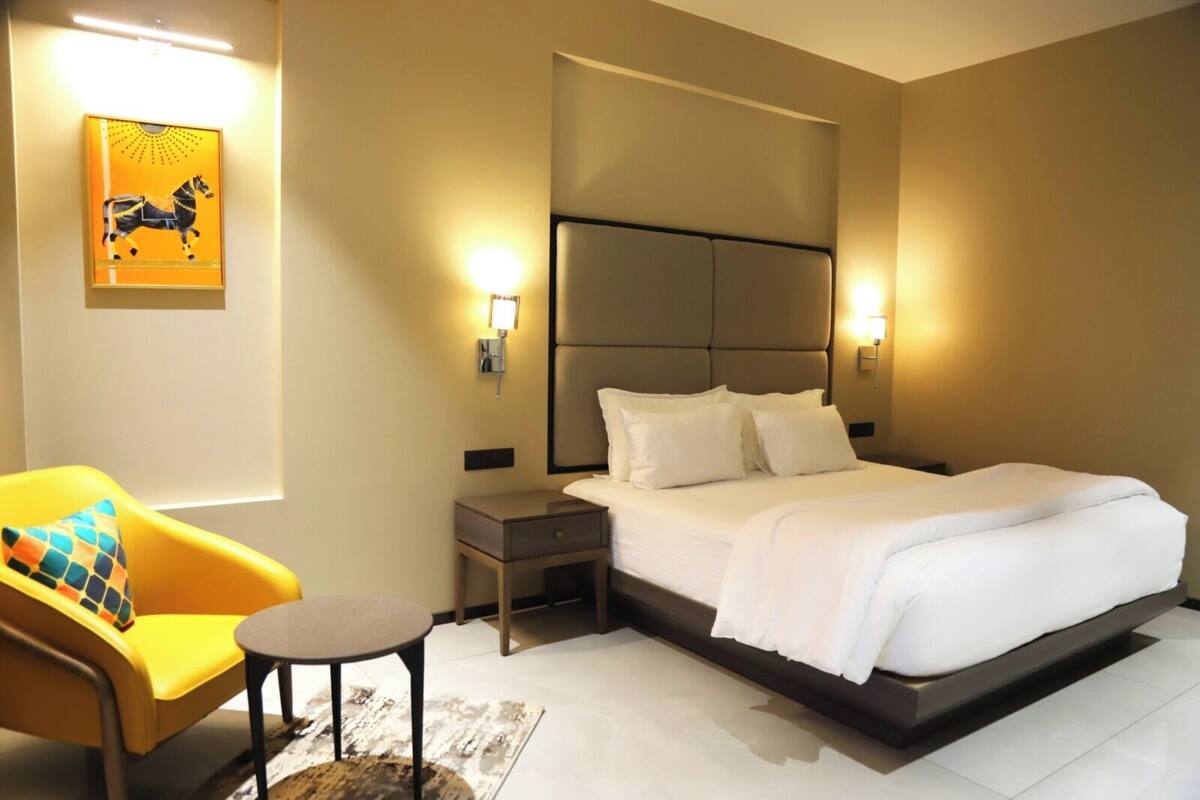 Une chambre d’hôtel comprenant un lit, des tables de chevet, une chaise et une œuvre d’art murale.