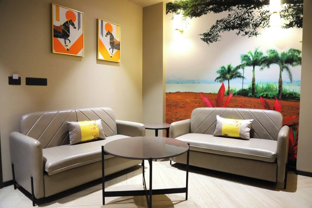 Une pièce comprenant deux canapés et une petite table, une fresque représentant un paysage, ainsi que deux œuvres d’art encadrées accrochées au mur.
